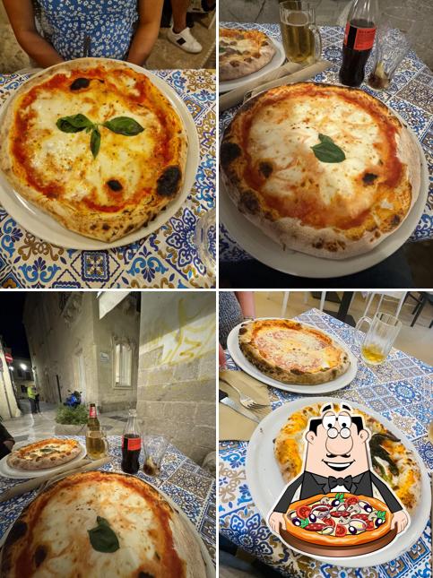 Margherita appena sfornata, con mozzarella a chiazze e una foglia di basilico al centro, su un tavolo di maiolica bianca e blu