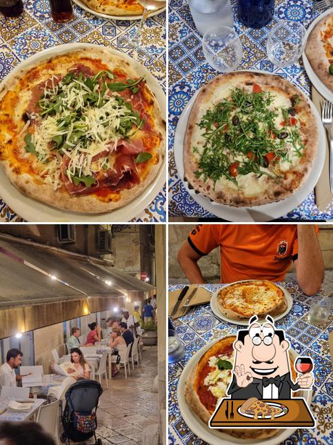 Pizza con fette di crudo, scaglie di formaggio e rucola aggiunte a crudo dopo la cottura, servita su un tavolo di maiolica